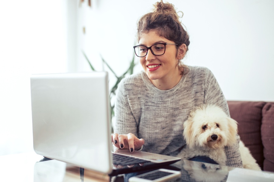 Woman on a laptop with a dog in her lap